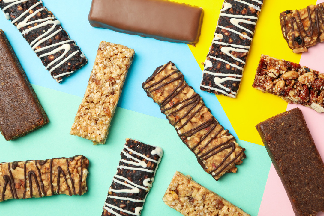 Tasty granola bars on multicolor background, top view